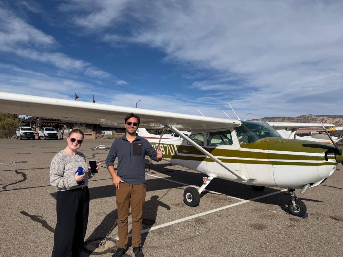 Two students beside N1287U at Sedona with red rocks behind
